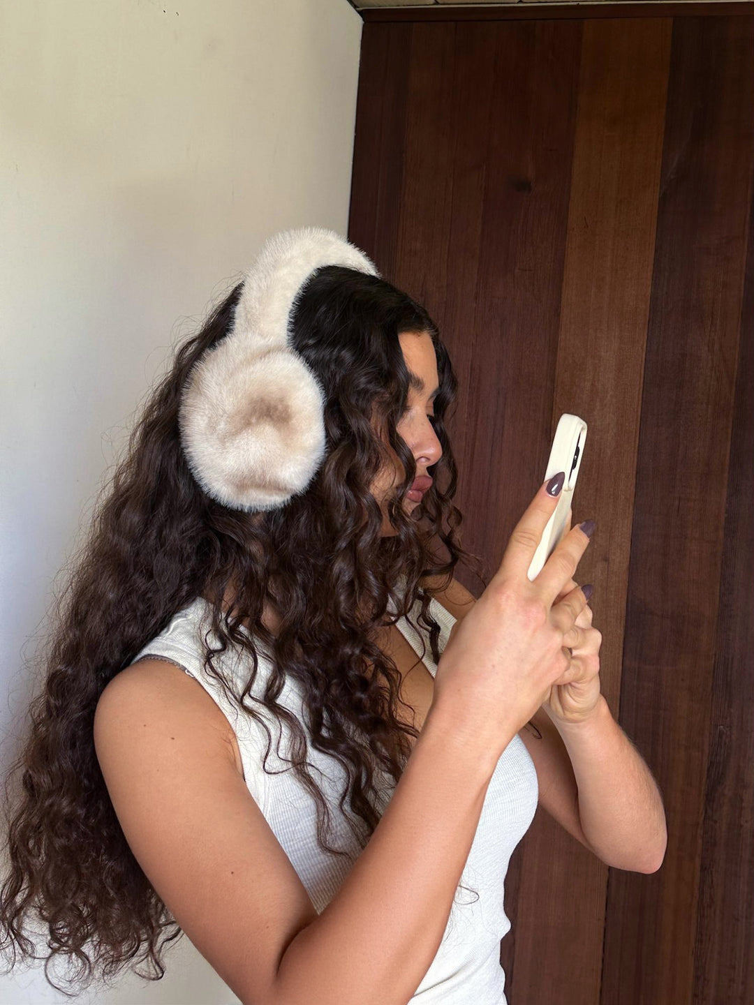 Model looking at phone while wearing Sugar Muffs.