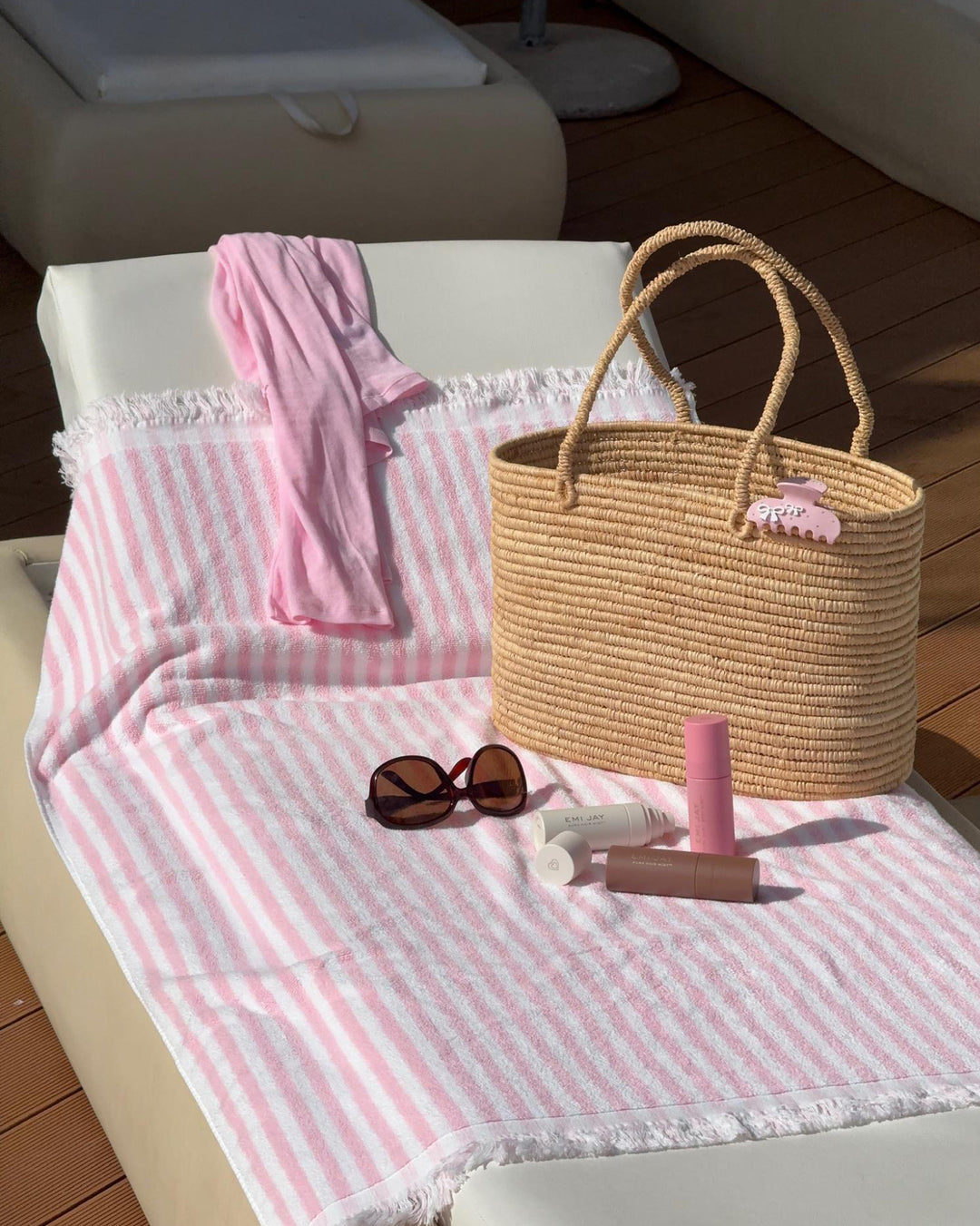 all three Aura Mist scents next to sunglasses and bag with sweetheart clip on chair with pink and white stripe towel