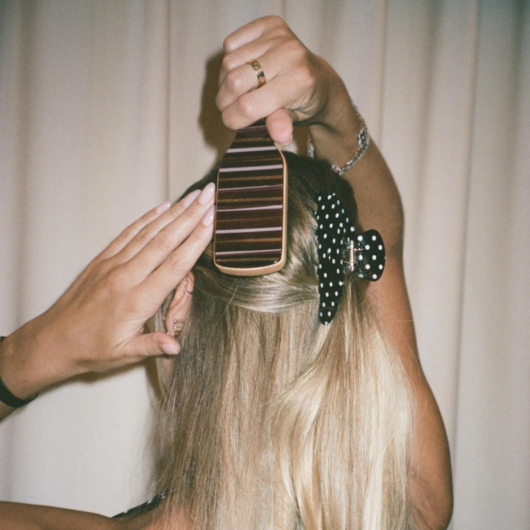 model wearing big effing clip while brushing hair with Mini Boar Bristle Brush in Nightcap