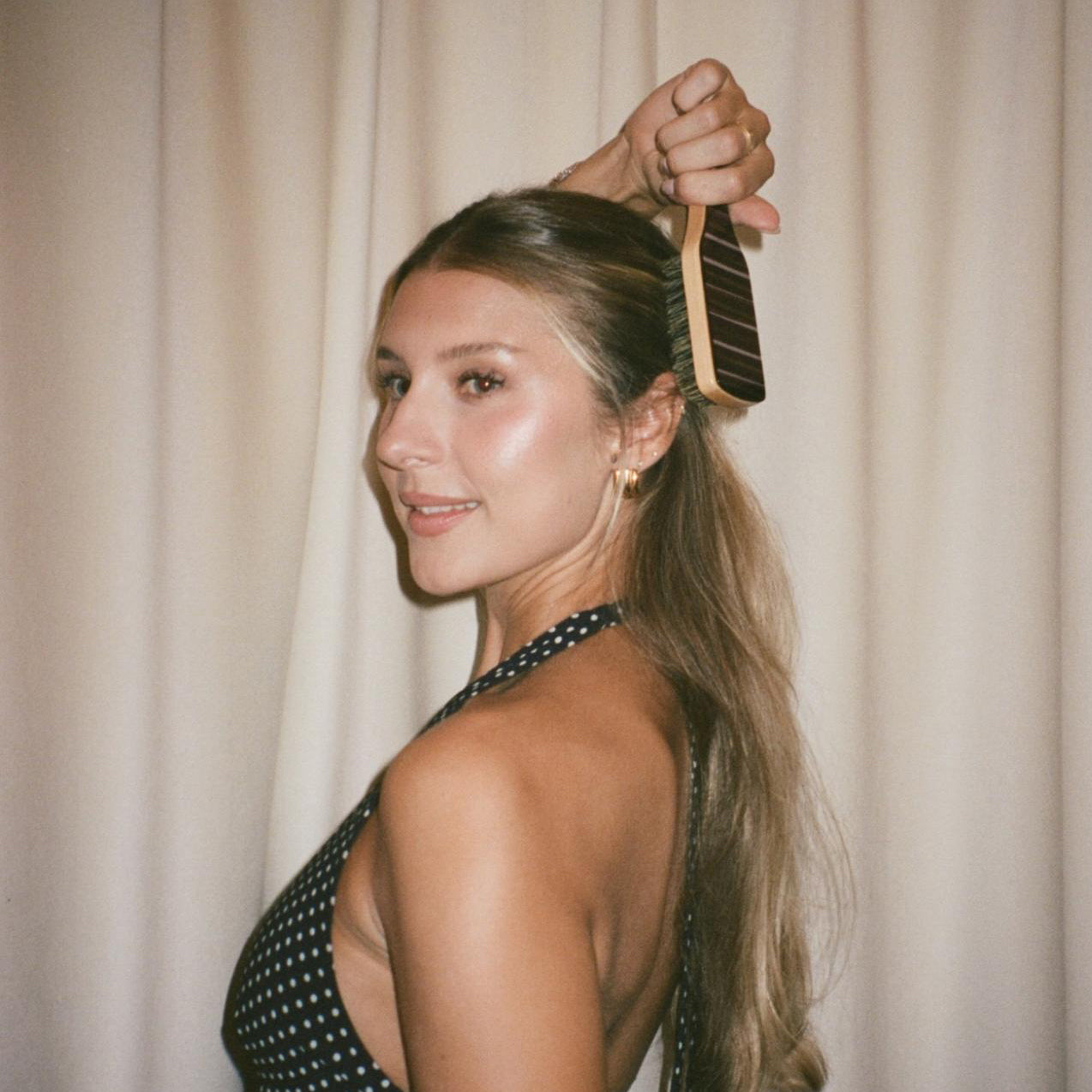 model in polka dot dress brushing hair with Mini Boar Bristle Brush in Nightcap