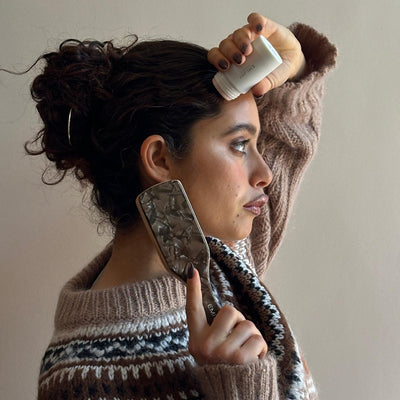 Model applying Angelstick to hair while holding Mini Boar Bristle Bamboo Brush in Toasted Sugar.