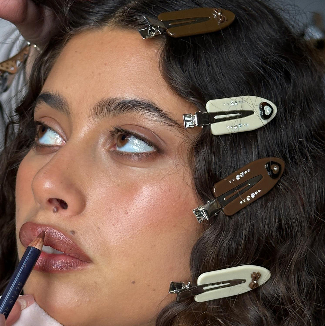 Close-up of model wearing Popstar Clips in Hazelnut Hug in hair while applying lip liner.