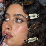 Close-up of model wearing Popstar Clips in Hazelnut Hug in hair while applying lip liner.