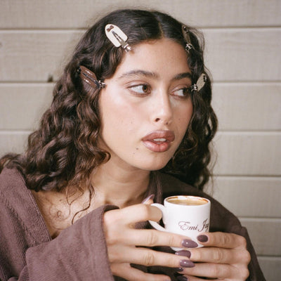 Model wearing Popstar Clips in Hazelnut Hug while holding Emi Jay mug of coffee.