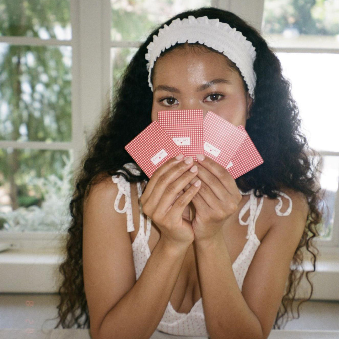 model holding playing cards in front of face while wearing Ruffle Headband in Daffodil in hair
