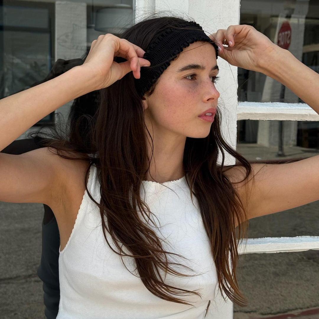 model looking away while adjusting Ruffle Headband in Noir in hair