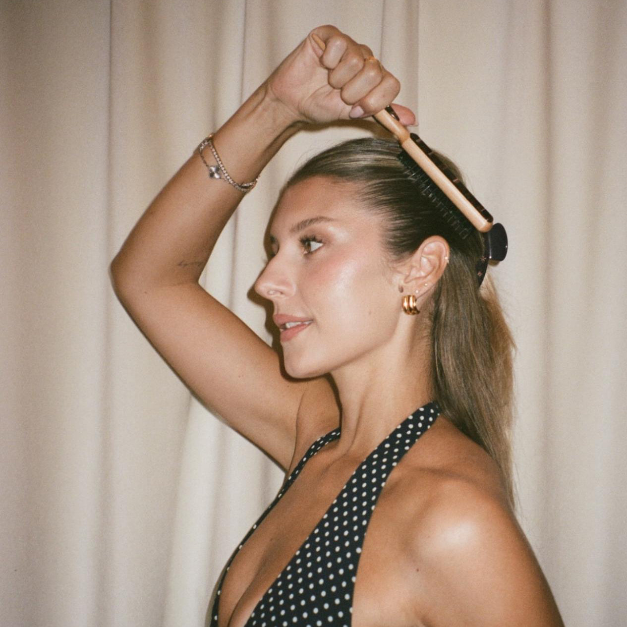 model in polka dot dress brushing hair with Styling Brush in Nightcap