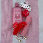 Aura Hair + Body Mist in Lychee Baby with assorted Emi Jay hair accessories on pink and white striped towel