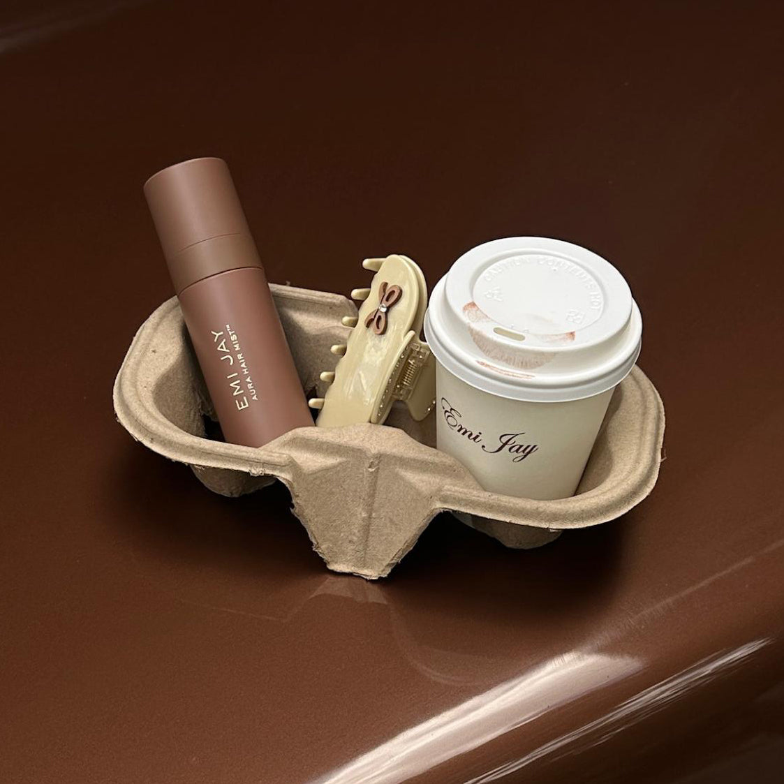 Aura Hair + Body Mist in Toasted Sugar, Sweetheart Clip in Vanilla Chai and coffee in a tray on a car.