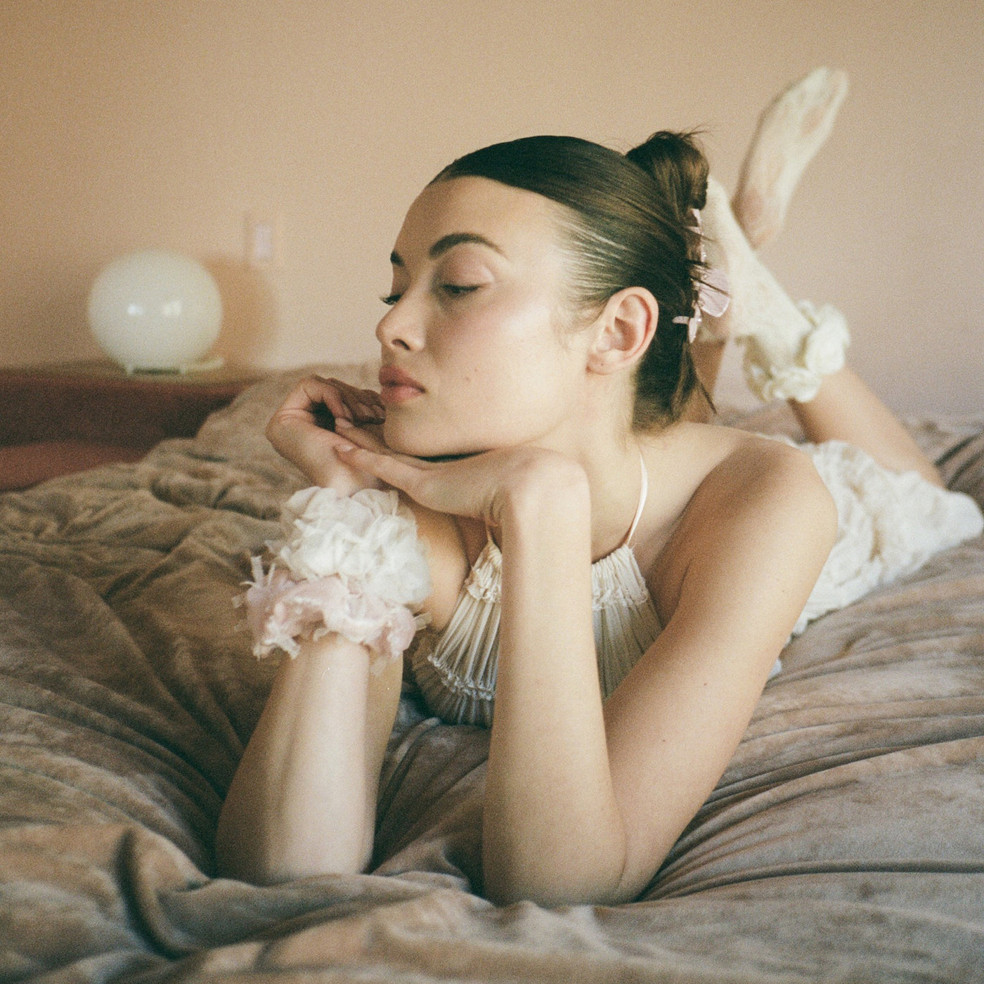 model laying on bed with Tutu Scrunchie in Ballet on wrist