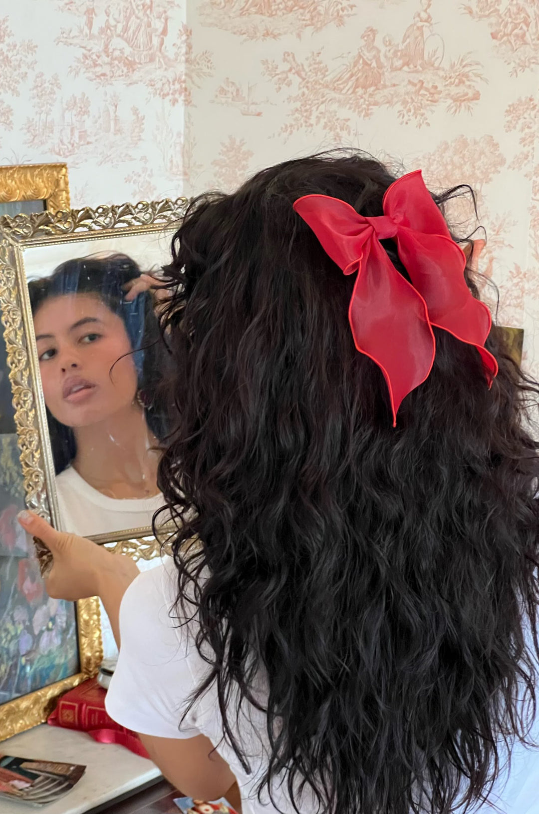 model looking in mirror while wearing bow barrette in cherry kiss 