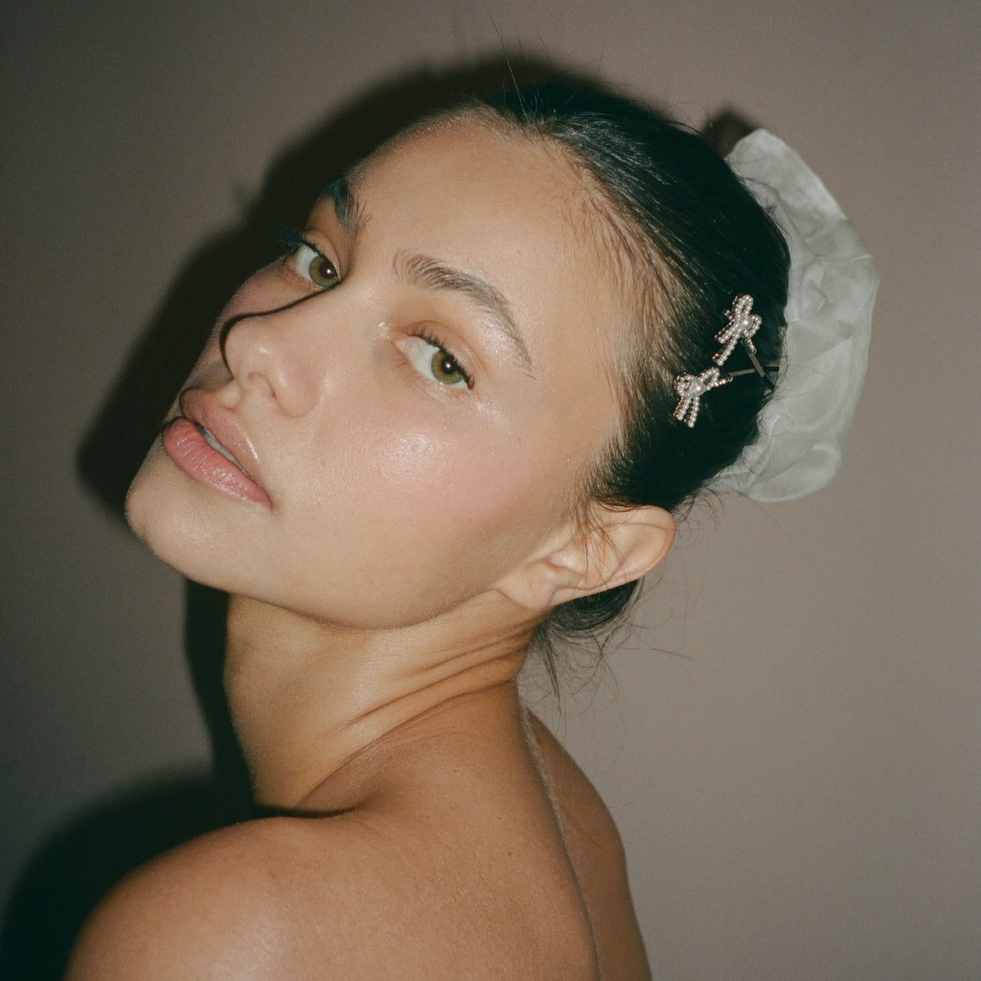 closeup of model titling head with Cloud Scrunchie in Storm Silk Organza + Barrette Set in Take a Bow in hair